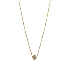 A delicate gold chain necklace featuring a small, raw, faceted diamond pendant, shown against a solid white background.