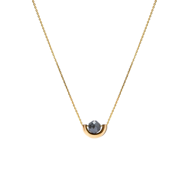 A delicate gold chain necklace featuring a small, polished gold crescent-shaped setting holding a round, dark gray diamond, presented on a solid white background.
