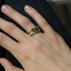 A close-up of a person's hand wearing three delicate gold rings with small round-cut diamonds.
