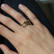 A close-up of a person's hand wearing three delicate gold rings with small round-cut diamonds.