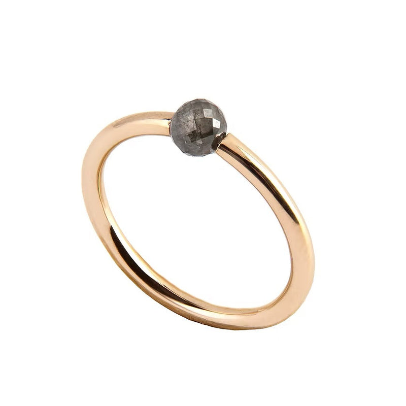A minimalist yellow gold ring featuring a single, small, round grey faceted diamond, shown on a plain white background.
