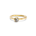 A delicate gold ring with a small, round, pale grey diamond in a bezel setting, shown on a plain white background.