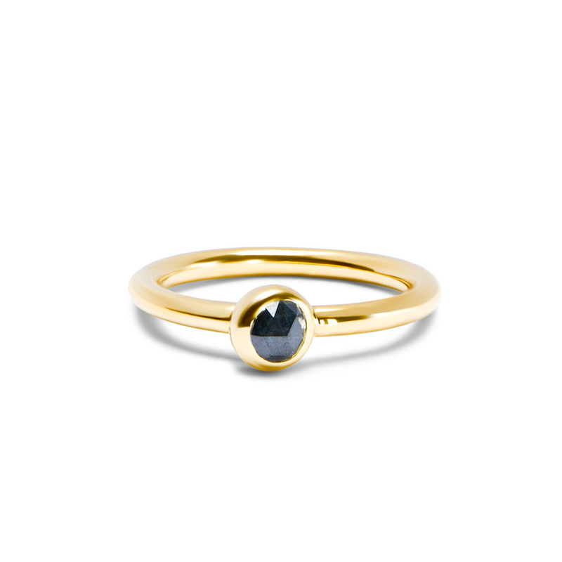A yellow gold ring with a single faceted dark ocean blue gemstone in a bezel setting, shown on a clean white background.
