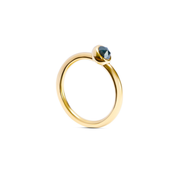 A yellow gold ring with a single faceted dark ocean blue gemstone in a bezel setting, shown on a clean white background.