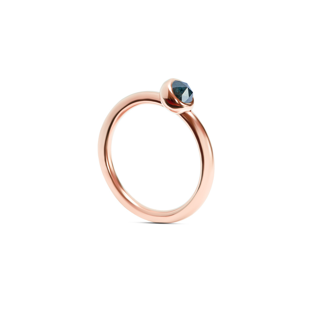 A rose gold ring with a single faceted dark ocean blue gemstone in a bezel setting, shown on a clean white background.