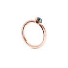 A rose gold ring with a single faceted dark ocean blue gemstone in a bezel setting, shown on a clean white background.