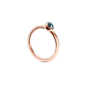 A rose gold ring with a single faceted dark ocean blue gemstone in a bezel setting, shown on a clean white background.