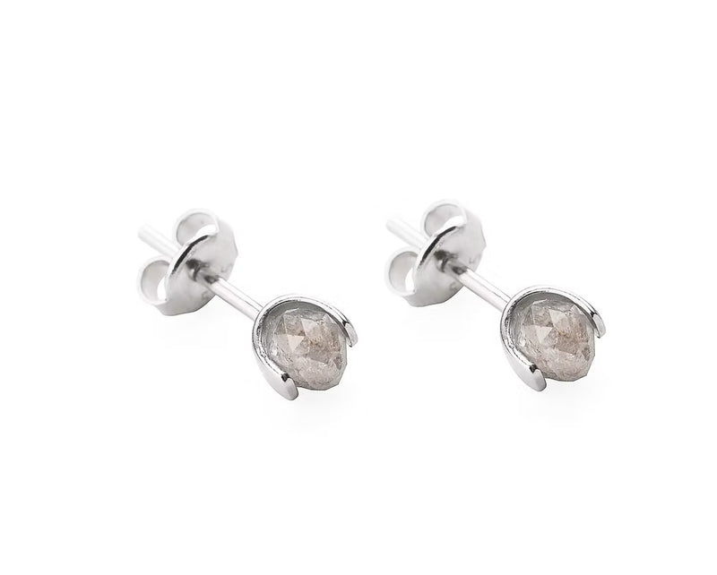A pair of gold stud earrings with faceted gray diamonds in a prong setting, shown on a clean white background.