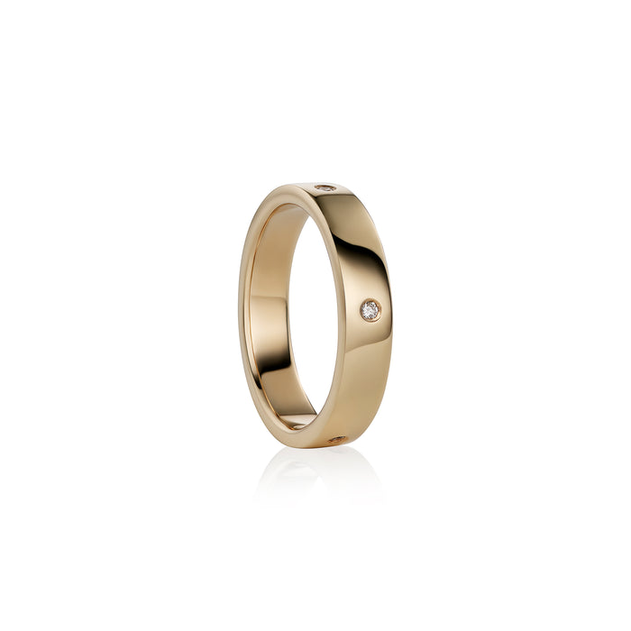A polished yellow gold band ring with  small round-cut diamonds set on the side, shown against a clean white background with a soft reflection.