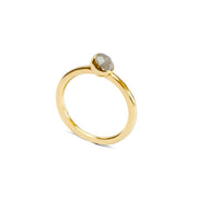 A delicate gold ring with a small, round, pale grey diamond in a bezel setting, shown on a plain white background.