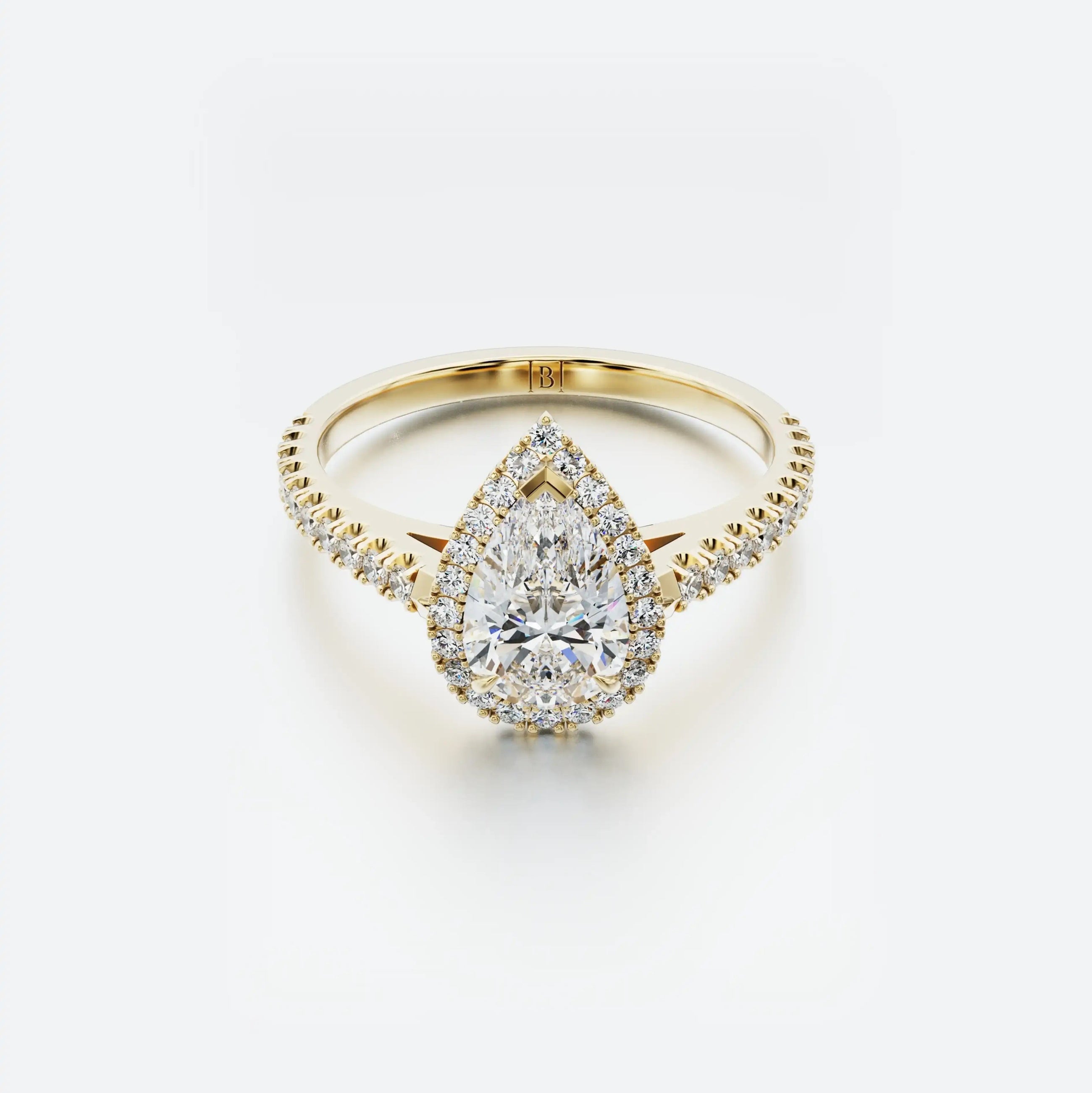 Gold ring with a pear-shaped diamond on a white background