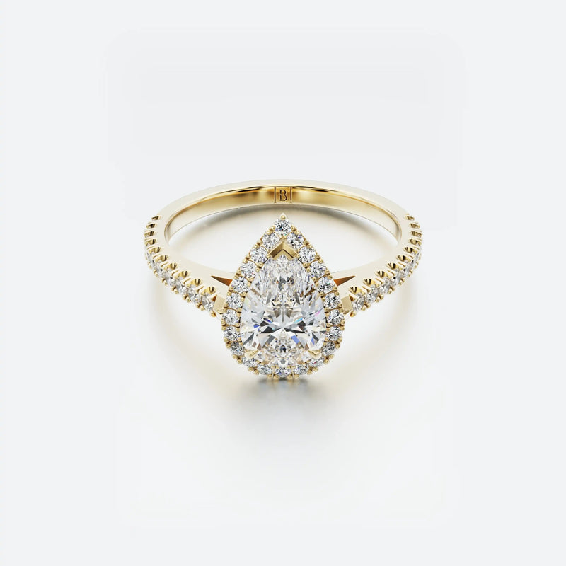 Gold ring with a pear-shaped diamond on a white background