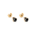 A pair of gold stud earrings with faceted black diamonds in a bezel setting, shown on a plain white background.