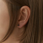 A pair of gold stud earrings with faceted gray diamonds in a prong setting, shown on a clean white background.