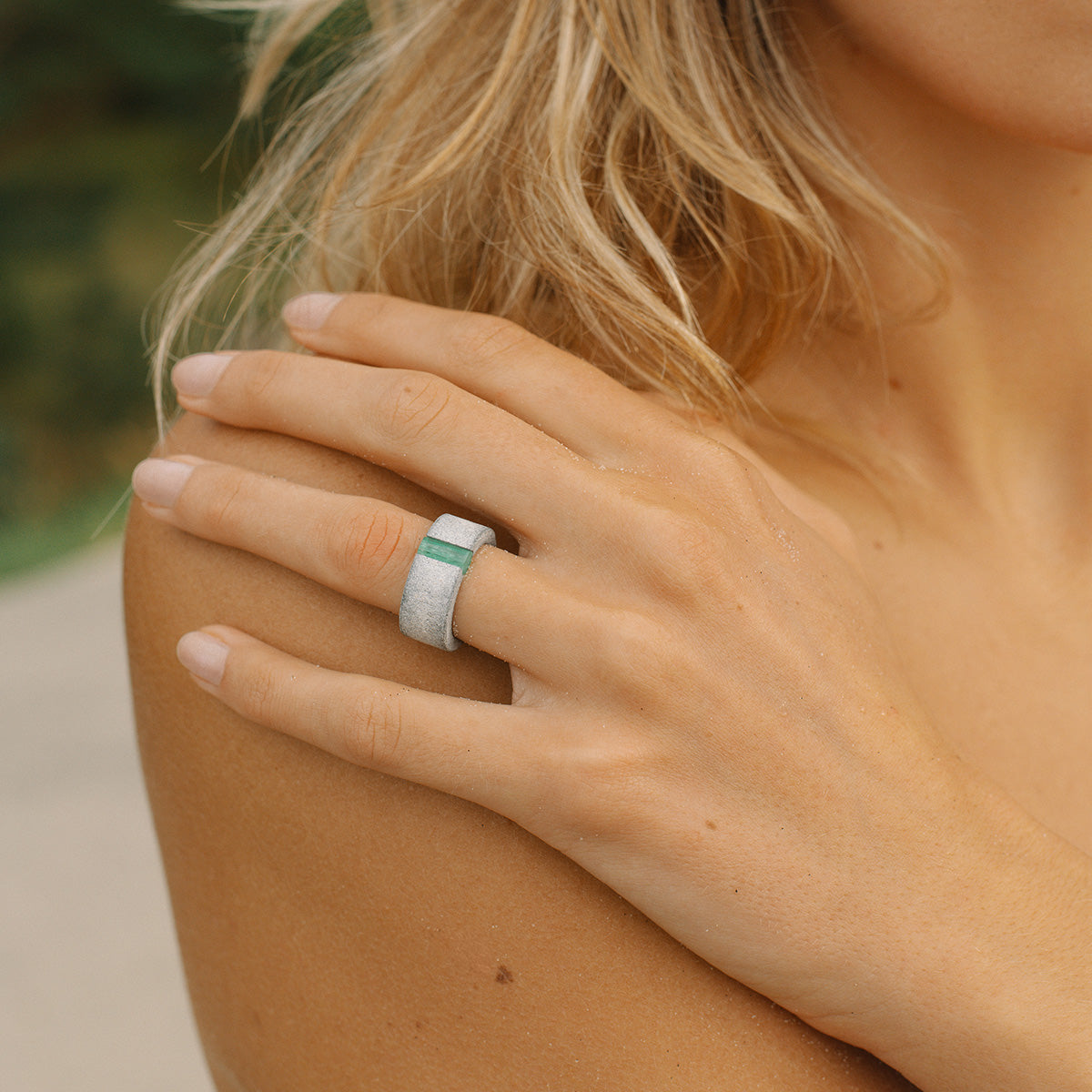 Hand wearing one-of-a-kind ring composed of tantalum and rough Columbian emerald by ASR JWLS.