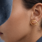 Close-up of a person wearing a gold earring with a blue garment in the background