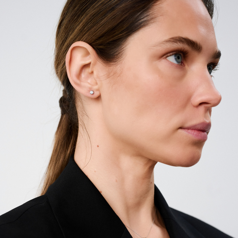 Woman wearing stud earrings featuring round brilliant-cut diamonds set in 14k white gold.