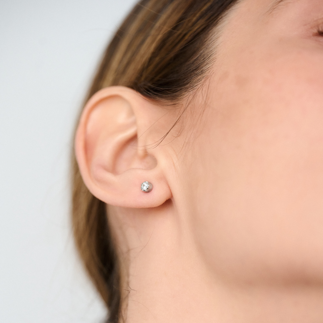 Woman wearing stud earrings featuring round brilliant-cut diamonds set in 14k white gold.