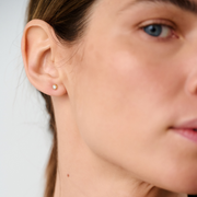 Woman wearing stud earrings featuring round brilliant-cut diamonds set in 14k yellow gold.