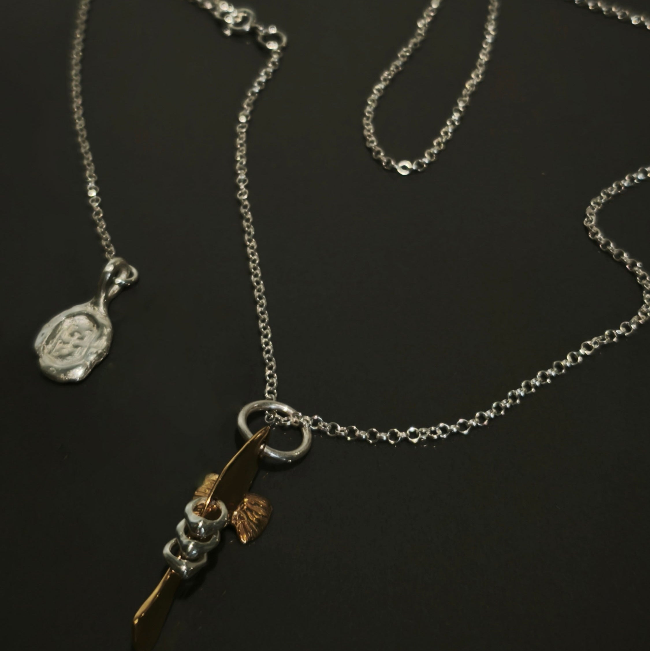 Silver necklace with a fish pendant on a dark background