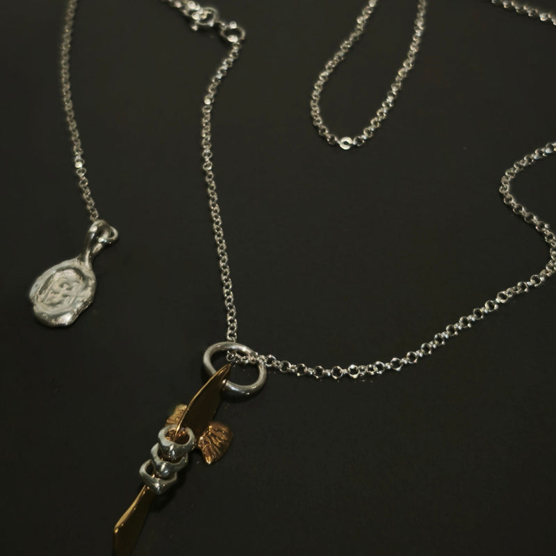 Silver necklace with a fish pendant on a dark background