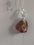Amber pendant with silver chain on a plain background