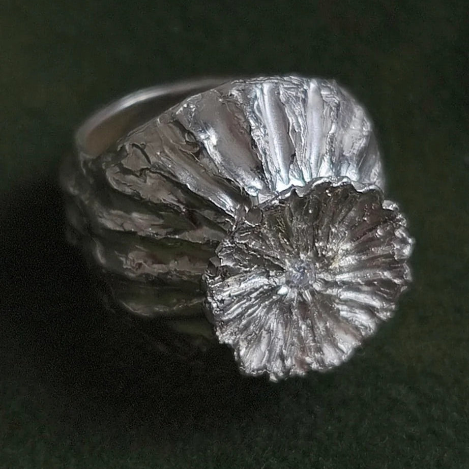 Silver ring with textured design on a dark background
