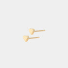 Pair of gold hart-shaped stud earrings on a light beige background