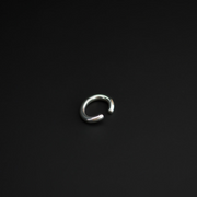 A polished silver-toned metal open-ended ring ear cuff, shown on a plain black background.