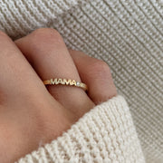 Hand wearing yellow gold ring with word Mama set with single diamond.