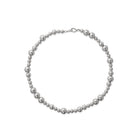 A silver necklace with varying sizes of beads, displayed against a white background.