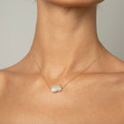 Woman wearing unique baroque-shaped freshwater pearl suspended from a delicate yellow gold chain. 