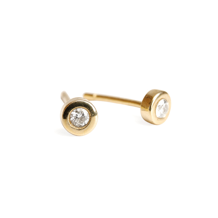 A pair of 14k yellow gold stud earrings with a single white diamond on each, set against a plain background.