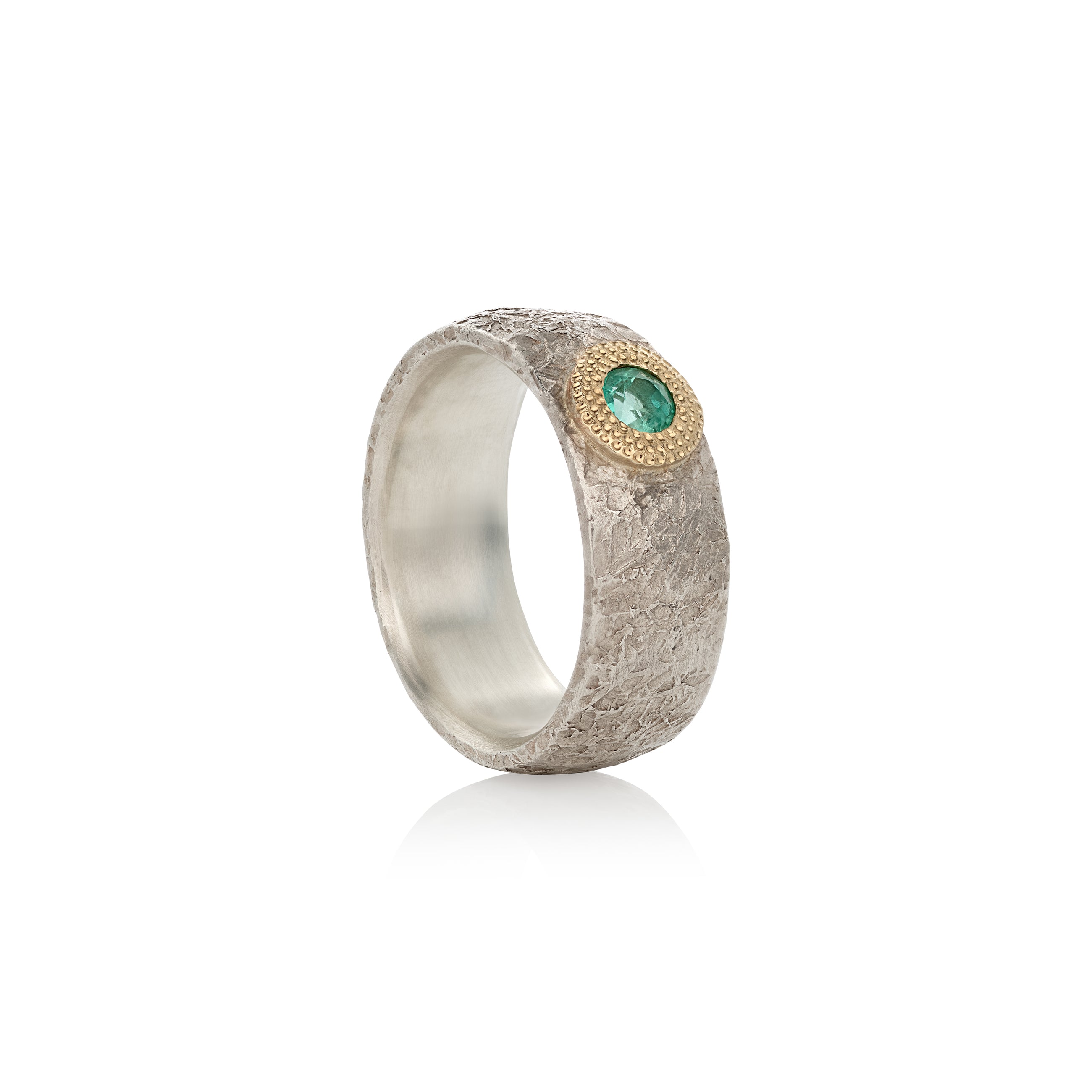 A silver ring with a central emerald and gold detailing, presented against a white background.