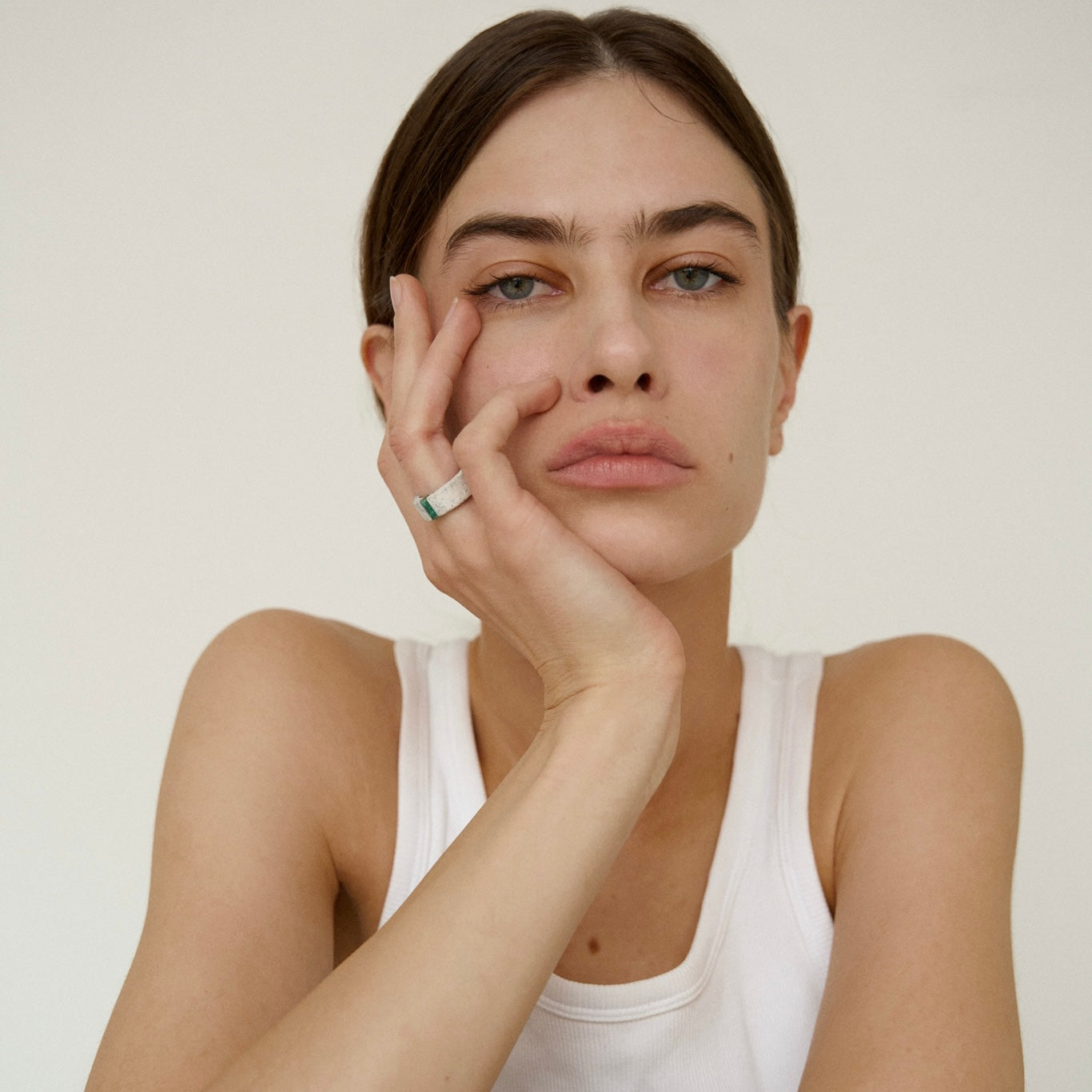 Woman wearing one-of-a-kind ring composed of tantalum and rough Columbian emerald by ASR JWLS.