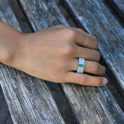 Hand wearing one-of-a-kind ring composed of tantalum and rough Columbian emerald by ASR JWLS.