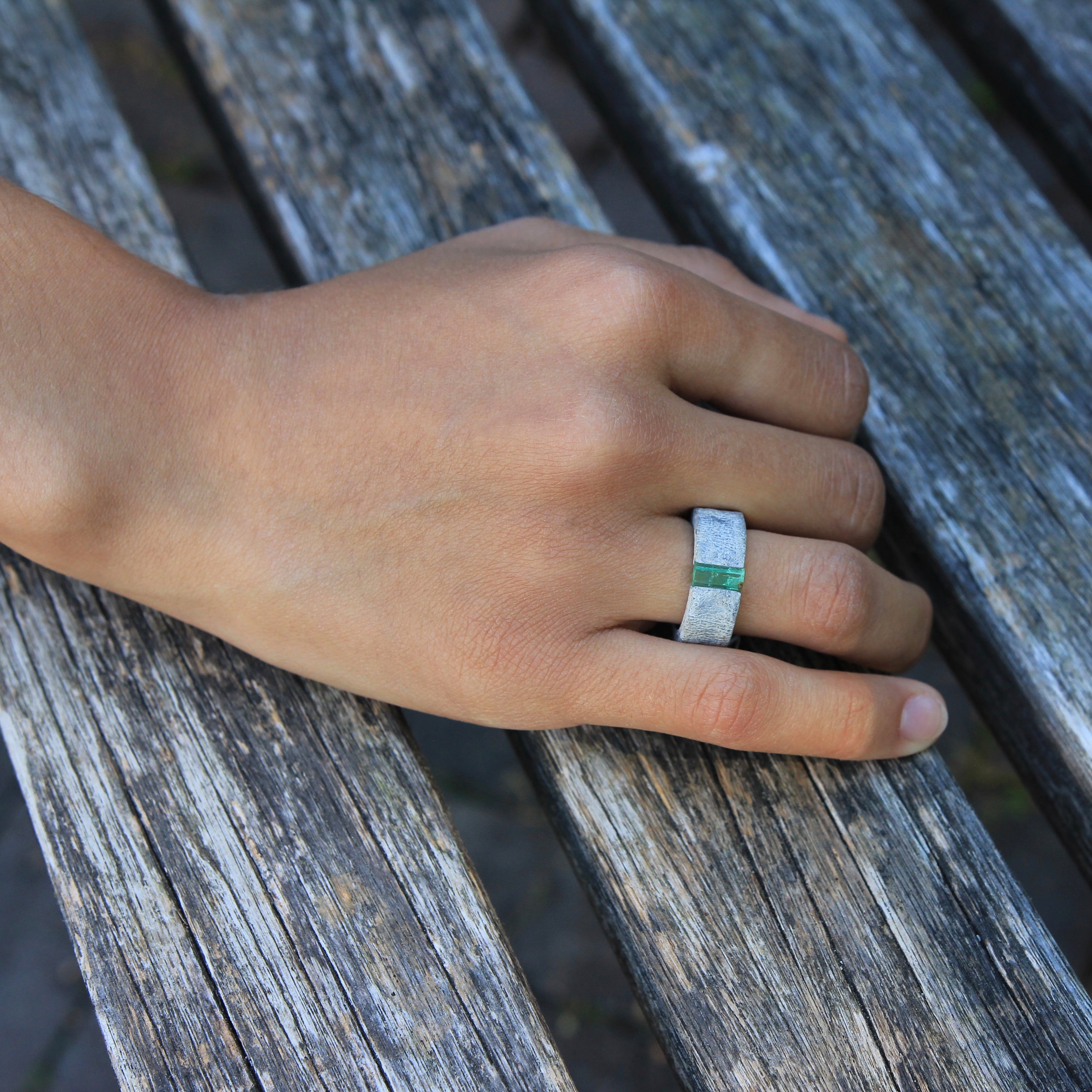Hand wearing one-of-a-kind ring composed of tantalum and rough Columbian emerald by ASR JWLS.